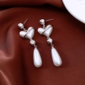 Detail of vintage silver pearl heart earrings on elegant dark red silk fabric - Silver