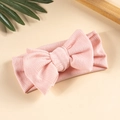Gros plan d'un bandeau rose tricoté pour bébé avec un grand nœud et texture en losange - Rose Clair
