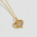 Detailed close-up of double-layered gold heart pendant necklace with shimmering crystals - Heart