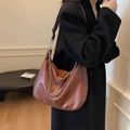 Brown retro hobo bag with silver chain and white stitching on a model in black coat - Brown