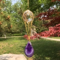 Detail of K9 crystal ball with purple agate slice suncatcher hanging in garden - Purple