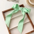 Detail van een muntgroene satijnen strik haarklem met lange linten op houten tray - Strik veerclip / Muntgroen