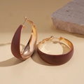 Detail of wide matte brown and polished gold round hoop earrings on a stone background - Brown