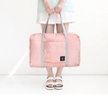 Pink and grey foldable nylon travel bag shown in hand for size demonstration - Pink
