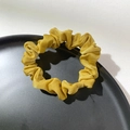 Detail of yellow satin hair scrunchie with pleated texture on a black aesthetic tray - Yellow