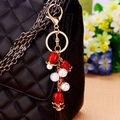 Floral bag charm with red transparent flower and white pearls on black leather bag - Pearl Pomegranate Flower
