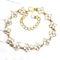 Detailed shot of golden four-leaf flower bracelet with micro-paved white zircons - Flower / Gold