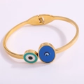 Close-up of golden titanium steel hinged bracelet with blue and green evil eye charms - Gold Enamel Eye Open Bangle