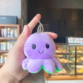 Plush flip octopus keychain in purple and green held in hand for bag decoration - Purple