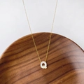 Collier en titane doré avec pendentif lettre Q en nacre sur un plateau en bois - Lettre Q