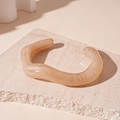 Macro shot of apricot marble pattern resin bangle on a textured beige stone surface - Pink