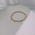 Detail view of gold bead bracelet with a pearl charm and cat paw pendant on silk fabric - Gold-Dog Paw