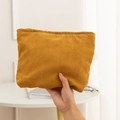 Detailaufnahme der Textur der senfgelben Cord-Kosmetiktasche in der Hand - Schokoladenbraun