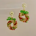 Detail of handmade beaded Christmas wreath earrings with gold snowflake stud and red accents - Snowflake Christmas Wreath-Ear Clip