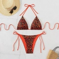 Flat lay of leopard print bikini with neck ties and side-tie bottoms on stone texture - Orange Leopard