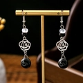 Detail of vintage flower earrings with black and white beads on a golden jewelry stand - Silver Rose Black-White Cat Eye (E1331-4)