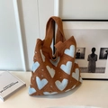 Close-up of knit heart pattern tote bag in brown and blue with soft woven texture - Caramel color
