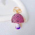Macro view of mushroom keychain with pink rhinestones and purple resin on golden ring - Single Mushroom / Purple