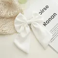 Detail of elegant large white fabric bow hair clip with long ribbons on soft background - White