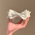 Detailopname van de haarklem met stippenstrikt en fonkelend middelpunt van strass - Crème Wit