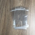 Transparent plastic self-sealing jewelry packaging bag on a dark wood surface - 1 Piece / Matching OPP Bag