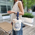 Cream canvas bucket bag with blue smiley face print and navy webbing handle - Happy Face