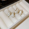 Detailed view of bow earrings with pearl white coating and gold edges in a white jewelry box - 62# Gold & White Bowknot