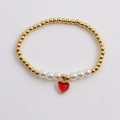 Elastic beaded bracelet with gold copper beads, white pearls and a red heart charm - Red