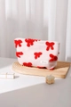 Gros plan sur la trousse de maquillage en peluche rose avec nœuds brodés rouges et logo - 26x18cm / Rouge Grand