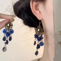 Detail view of vintage style blue glass bead tassel earrings worn on model's ear - Hook Style / Sapphire Blue