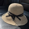 Detailed view of hand-woven raffia sun hat with black grosgrain ribbon and bow accent - M (56-58cm) / Natural