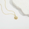Golden sunburst evil eye pendant necklace with white zircon on white stone background - Evil Eye