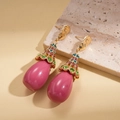 Detailed macro view of gold-tone teardrop earrings with pink beads and colorful rhinestones - Pink