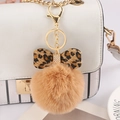 Detail of 8cm light brown faux fur pom pom keychain with leopard bow on a white handbag - Camel - Leopard Bow