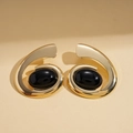 Detailed view of gold spiral earrings with inlaid large black oval gemstones on beige background - Earrings-Gold (Steel Needle)