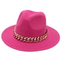 Détail du chapeau Panama fuchsia avec une grosse chaîne dorée sur texture tressée - Chapeau de Paille à Bord Plat / Rose rouge