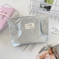 Detailansicht der silbernen Kosmetiktasche mit Knitteroptik auf weißem Schreibtisch - Silber