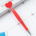Red heart-shaped twist ballpoint pen with silver metal trim on white grid background - Red