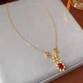 Detail einer Vintage-Goldkette mit ovalem rotem Edelstein-Anhänger auf grauem Kissen - Halskette-Gold-Rot