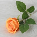 Single realistic orange velvet artificial rose with green leaves on white plush background - Orange