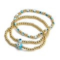 Close-up of three Evil Eye beaded bracelets featuring gold beads and blue resin charms - Layered Blue White Eye Gold Style (BE843MI06)