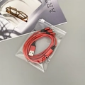 Dettaglio del cavo di ricarica intrecciato rosso in una custodia in PVC trasparente con zip - 9x13cm