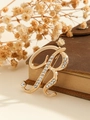 Elegant gold letter R brooch with sparkling crystals on a vintage book background - Gold Letter R