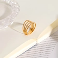 Detailed close-up of a layered gold-plated ring with hammer texture on an open book - 4-Layer Stripe Open Ring