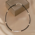 Minimalistische schwarze Perlenkette mit weißen Barockperlen auf beigem Seidenstoff - Schwarze Perlen und Weiße Barockperlen Kette (W-b-009)