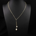 Elegante goldene Pulloverkette mit zwei Süßwasserperlen auf schwarzer Büste - Minimalistischer Metallstil