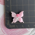 Macro view of a pink resin butterfly charm with a small rose and ruler for scale - Pink Butterfly + Red Rose