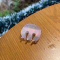 Close-up of pink glitter acetate hair claw clip with colorful shimmer on wooden background - Oval M Small Claw / Pink Glitter