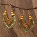 Detailed view of bohemian hollow carved gold earrings with turquoise bead accents - Antique Gold K-1387