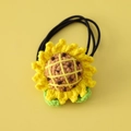 Detailed view of handmade crochet sunflower hair tie with yellow petals and green leaves - Sunflower